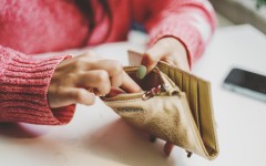 File: A woman looking for money in a wallet. GettyImages/Carol Yepes