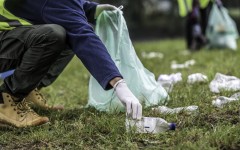 File: A volunteer picking up a plastic bottle during a park clean-up action. GettyImages/vm