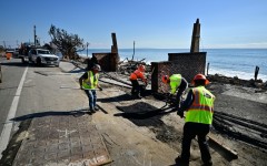 Workers on January 17, 2025 repair a road damaged by a fire that tore through the Los Angeles area 