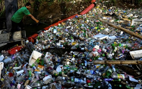 An NGO employee works on a gigantic hydraulic and solar-powered machine that collects garbage from the Juan Diaz River in Panama City