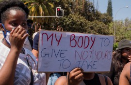 File: A protester holds a placard during a GBV protest.AFP/Hildegard Titus