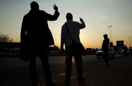 File: Commuters hold up their hands to signal to oncoming taxis their desired destination.