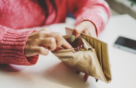 File: A woman looking for money in a wallet. GettyImages/Carol Yepes