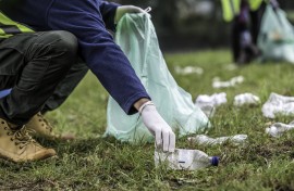 File: A volunteer picking up a plastic bottle during a park clean-up action. GettyImages/vm