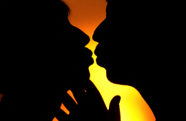 File: An illustrated picture shows a man and a woman kissing in front of the sunset.