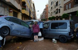 Residents stand in front of piled up cars following deadly floods in Alfafar neighbourhood, south of Valencia