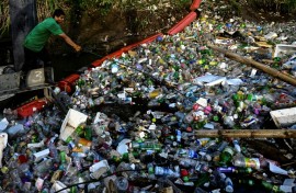 An NGO employee works on a gigantic hydraulic and solar-powered machine that collects garbage from the Juan Diaz River in Panama City