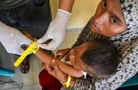 Rohingya refugees receive identity wristbands from UNHCR staff at a temporary shelter in Labuhan Haji, Indonesia