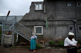 Local residents whose homes have been destroyed by the Chido cyclone stand in front of a damaged building in the village of Sohoa, on the French Indian Ocean territory of Mayotte