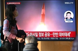 People watch a television screen showing a news broadcast with file footage of a North Korean missile test, at a train station in Seoul