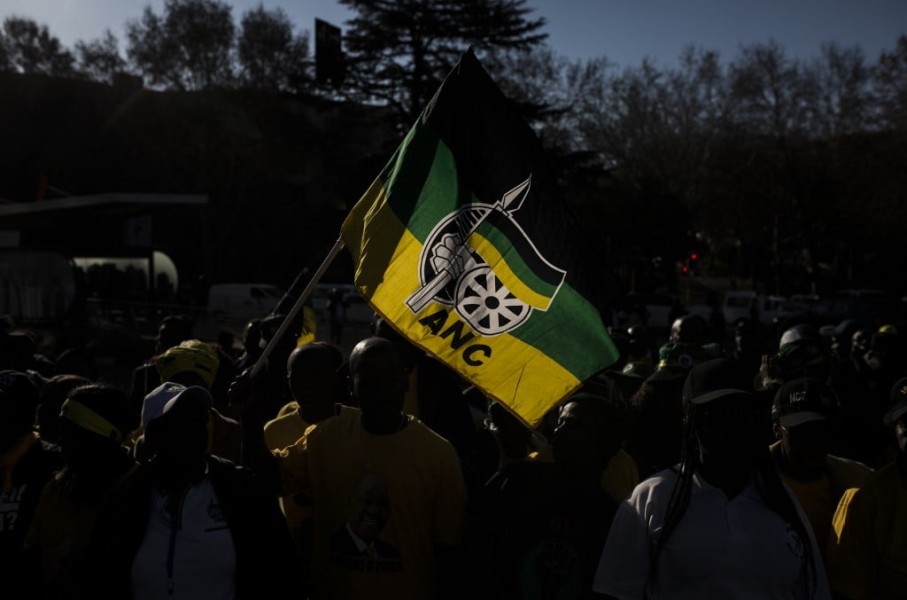 A man holds a flag of the South African ruling party African National Congress (ANC), as he gathers with supporters of former South African President Jacob Zuma outside House Hill building during the former South African president appearance at the Zondo Commission in Johannesburg, South Africa on July 15, 2019.