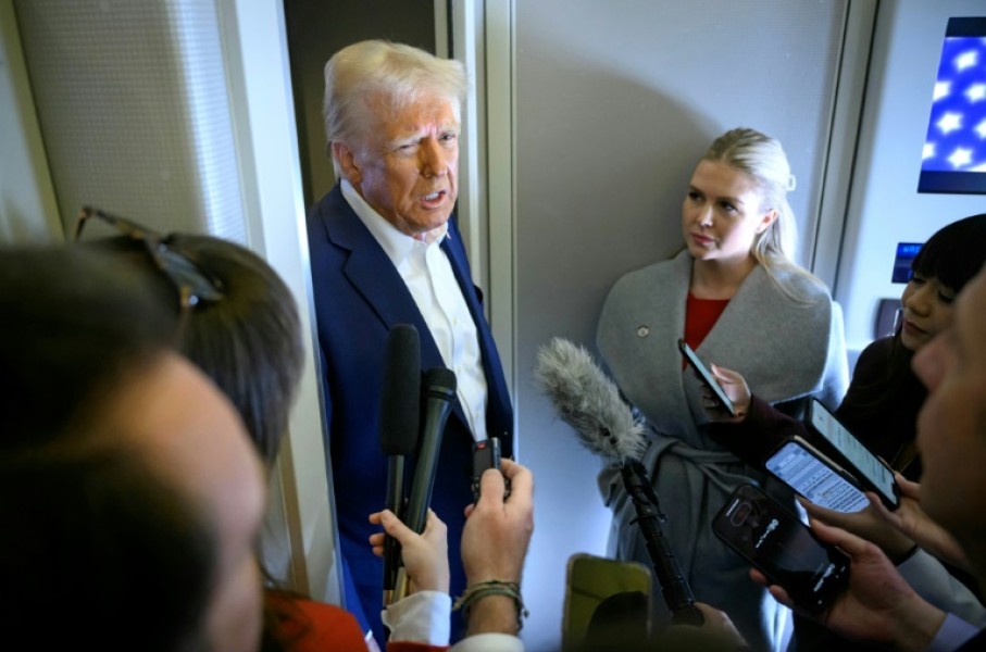 US President Donald Trump speaks with the press, alongside White House Press Secretary Karoline Leavitt (R), on board Air Force One 