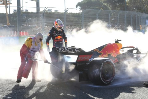 A marshal wields a fire extinguisher as Max Verstappen looks at his stricken Red Bull at the 2022 Australian Grand Prix at the Albert Park Circuit in Melbourne