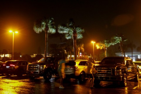 People fight the wind in a parking lot before Hurricane Nicole makes landfall in Jensen Beach, Florida 