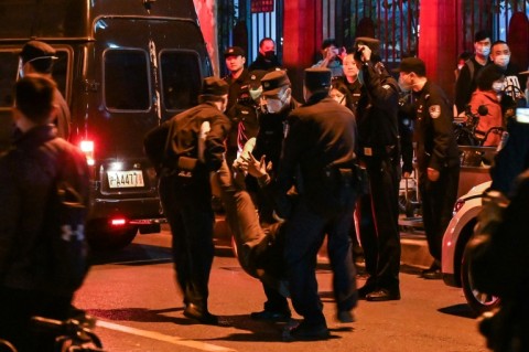 A man is arrested as people gather on a street in Shanghai where protests against China's zero-Covid policy took place the night before