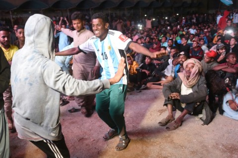 Pakistani football fans dance as they watch the live broadcast of the World Cup semi-final between Argentina and Croatia in the Lyari neighbourhood of Karachi