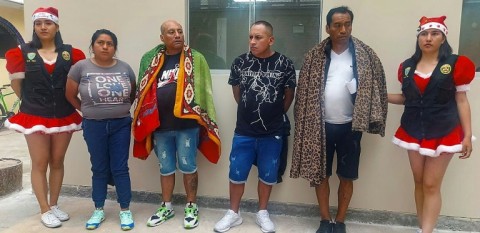 Members of Peru's National Police, dressed in holiday costume, stand near four suspected retail cocaine sellers arrested in a special operation 