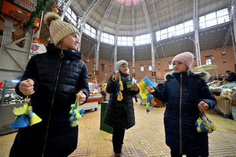 A woman and her daughters sell souvenirs to donate money to Ukrainian army ahead of the New Year's Eve celebrations in the center of the Ukrainian capital of Kyiv on December 31, 2022, amid the Russian invasion of Ukraine
