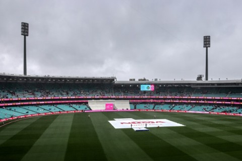 Ground staff stand near covers placed over the pitch during a rain delay on day three of the third cricket Test match between Australia and South Africa at the Sydney Cricket Ground