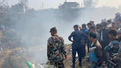 Rescuers and onlookers gather at the site of a plane crash in Pokhara, Nepal