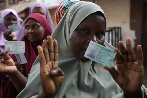 Women show their voter cards as they prepare to cast their ballots in governorship elections in Kaduna state in 2019