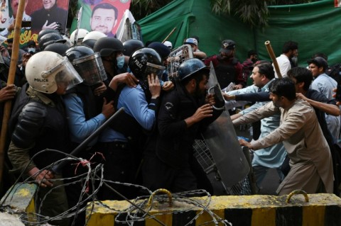 Supporters of former prime minister Imran Khan try to stop riot police from getting near his house in Lahore, eastern Pakistan