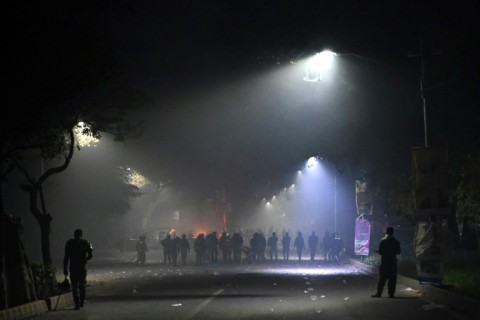 Police stand guard along a street near the residence of former Pakistan prime minister Imran Khan after clashes with his supporters