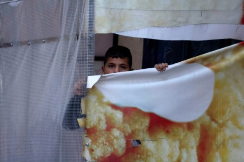 A Palestinian boy peeps at Israeli soldiers patrolling Huwara