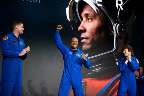 Artemis II pilot Victor Glover (C) pumps his fist on stage