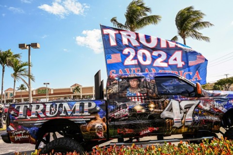 Supporters of former US president Donald Trump wait to greet him upon his arrival from New York near Palm Beach International Airport in Palm Beach, Florida 