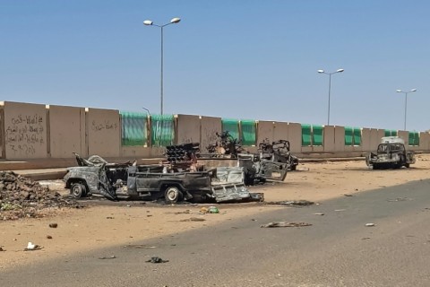 A column of smoke rises behind buildings near the airport area in Khartoum on April 19