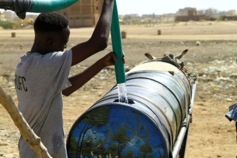 A man fills water into a barrel mounted on donkey-pulled carts in southern Khartoum on April 22, 2023, amid water shortages caused by the ongoing battles between the forces of two rival Sudanese generals