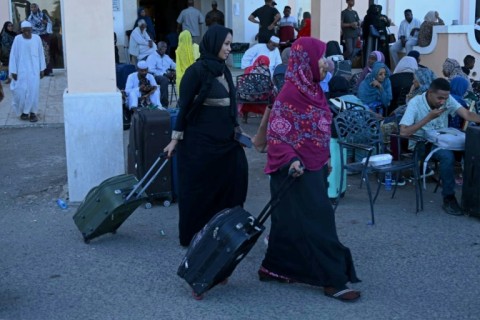 People wait with their luggage at Port Sudan ahead of their evacuation by sea