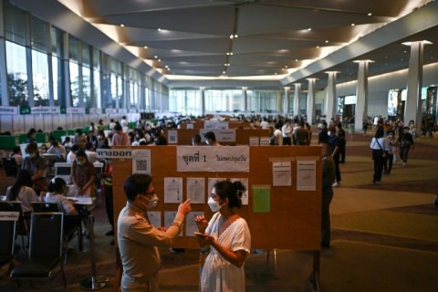 A voter (R) asks for directions to cast her ballot at a polling station inside a shopping mall in Bangkok