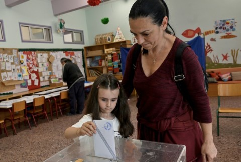 A child casts her mother's ballot at a primary school in Athens