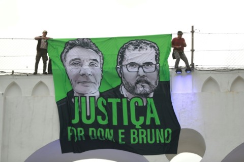 People unfurl a banner at a demonstration in Rio de Janeiro, Brazil, in June 2022, calling for justice for the murder of Phillips and Pereira