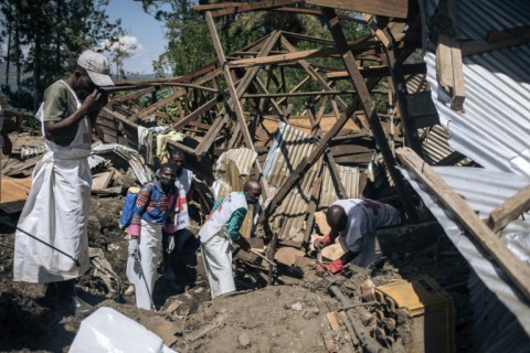 Local Red Cross volunteers attempt to extract a corpse from the rubble of a house destroyed by a landslide