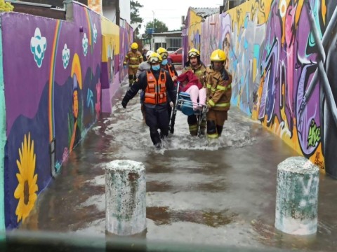 A handout picture released by the Rio Grande do Sul State Government shows firemen carrying a person in a flooded street in Porto Alegre, Rio Grande do Sul State, Brazil