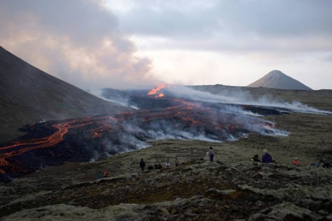 People watching the lava from a volcanic eruption near the Litli Hrutur peak, Iceland