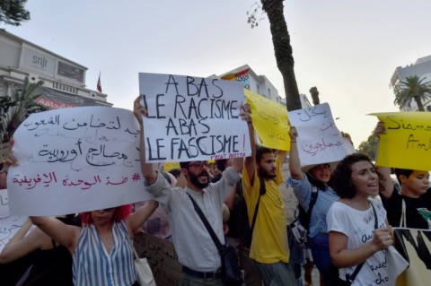 Demonstrators lift placards and chant anti-racism slogans during a protest in Tunis in support of migrants