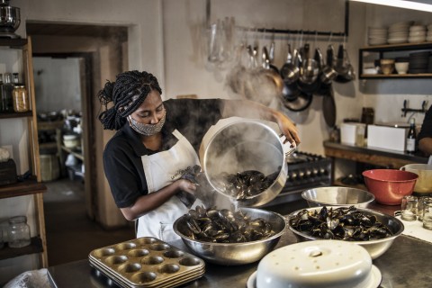 Emily, a cook with the South African chef Kobus van der Merwe of the Wolfgat restaurant on the beach in Paternoster, works on a steamy load of freshly cooked mussels in the restaurant’s kitchen.