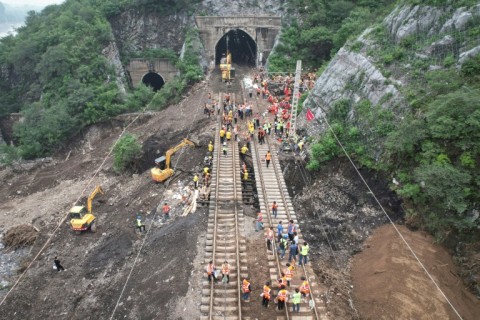 Workers repair a railway line in the aftermath of the flooding at a village following heavy rains 