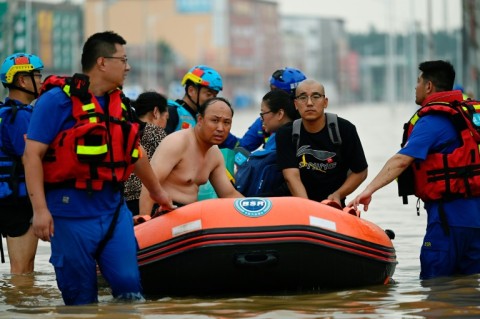 Rescuers wade in a flooded road as they evacuate residents following heavy rains in Zhuozhou, in northern China's Hebei province on August 2, 2023