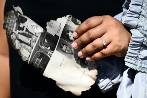 Davilynn Severson holds a page of a yearbook as she looks for belongings through the ashes of her family's home in the aftermath of a wildfire in Lahaina,  Hawaii 