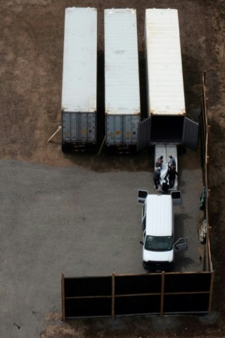 Workers move body bags into refrigerated storage containers adjacent to the Maui Police Forensic Facility where human remains are being stored in the aftermath of the Maui wildfires in Wailuku, Hawaii 