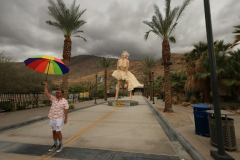 A person holds an umbrella in front of the "Forever Marilyn" statue, designed by US artist John Seward Johnson II, in Palm Springs as Hurricane Hilary heads toward southern California