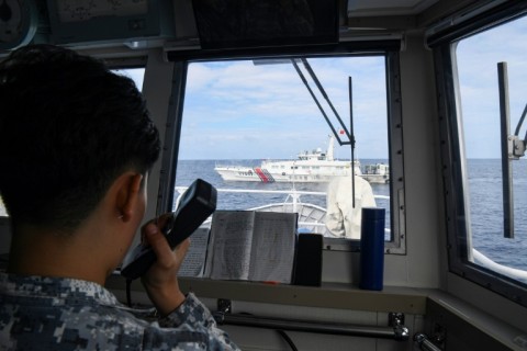 A member of the Philippine coast guard challenges a Chinese coast guard ship during a resupply mission to a Philippine navy ship in the disputed South China Sea