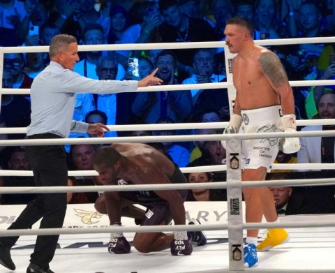 Ukraine's  reigning world heavyweight champion Oleksandr Usyk (R) waits as British challenger Daniel Dubois takes a knee during their bout in Wroclaw 