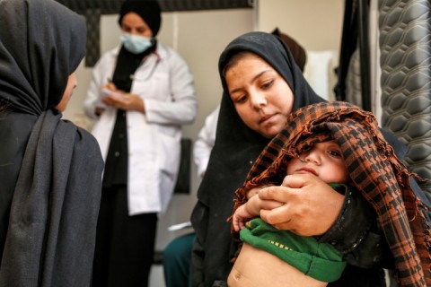 An Iraqi girl carries her brother, who suffers from intestinal colic, for examination in the village of Al-Ayyach