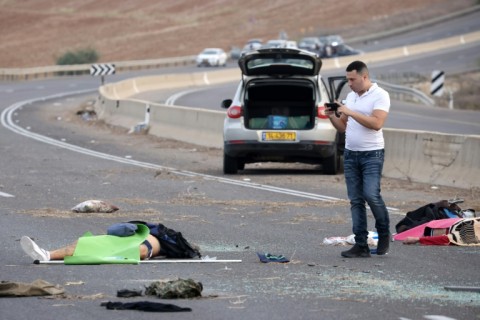 A man takes a picture of a body on a road close to the border with Gaza 